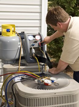 Air conditioner repairman checking levels of freon on units.