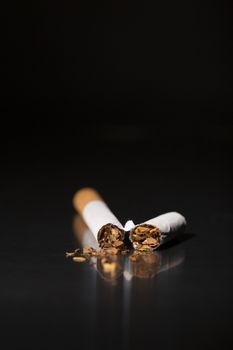 Broken cigarette on black background, reflected, stop smoking