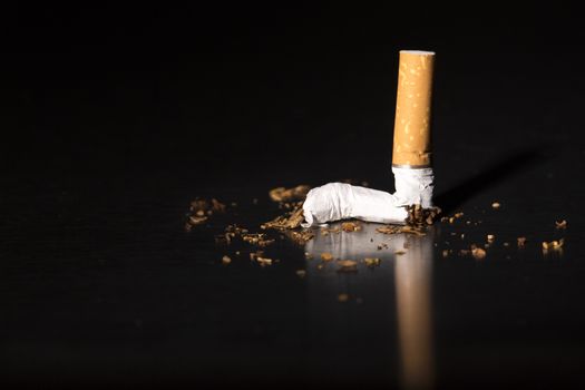 Broken cigarette on black background, reflected, stop smoking