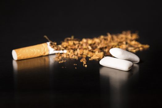 Broken cigarette on black background, reflected, stop smoking, with gum