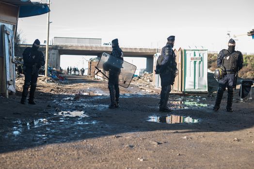 FRANCE, Calais: French riot police patrol on January 25, 2016, in a zone where makeshift shelters were cleared from in the migrant shantytown on the outskirts of Calais known as the Jungle, where thousands are trying to make their way across the English Channel.A prefectoral decree posted on January 19, 2016, gave people 24 hours to leave the premises of a 100-metre-wide strip of land in the jungle, where several small food businesses and restaurants had been set up, before its evacuation and destruction.