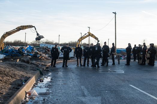 FRANCE, Calais: French riot police patrol on January 25, 2016, in a zone where makeshift shelters were cleared from in the migrant shantytown on the outskirts of Calais known as the Jungle, where thousands are trying to make their way across the English Channel.A prefectoral decree posted on January 19, 2016, gave people 24 hours to leave the premises of a 100-metre-wide strip of land in the jungle, where several small food businesses and restaurants had been set up, before its evacuation and destruction.