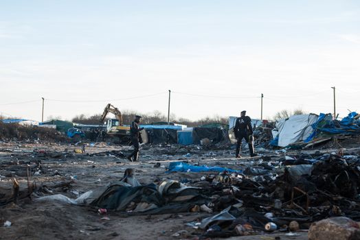 FRANCE, Calais: French riot police patrol on January 25, 2016, in a zone where makeshift shelters were cleared from in the migrant shantytown on the outskirts of Calais known as the Jungle, where thousands are trying to make their way across the English Channel.A prefectoral decree posted on January 19, 2016, gave people 24 hours to leave the premises of a 100-metre-wide strip of land in the jungle, where several small food businesses and restaurants had been set up, before its evacuation and destruction.