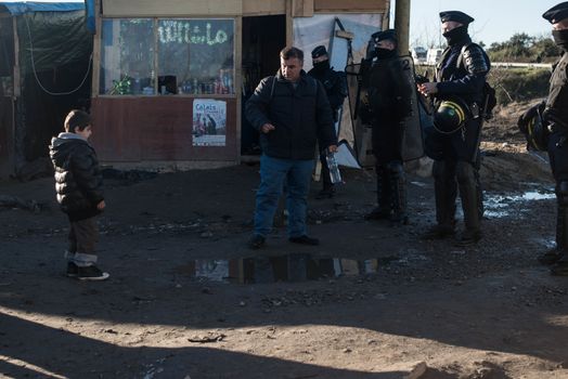 FRANCE, Calais: French riot police patrol on January 25, 2016, in a zone where makeshift shelters were cleared from in the migrant shantytown on the outskirts of Calais known as the Jungle, where thousands are trying to make their way across the English Channel.A prefectoral decree posted on January 19, 2016, gave people 24 hours to leave the premises of a 100-metre-wide strip of land in the jungle, where several small food businesses and restaurants had been set up, before its evacuation and destruction.