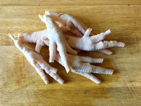 Chicken feet without toenails on a cutting board.