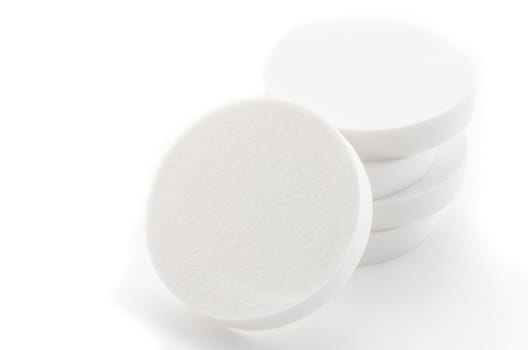 Cosmetic white circle sponges on white background.
