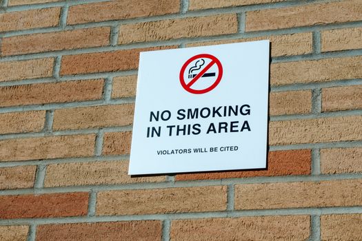 No smoking sign with red circle on brick wall.