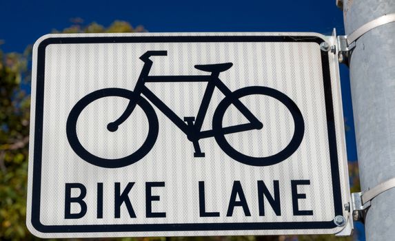 Bike lane parking sign with icon of bicycle and prominent black lettering.