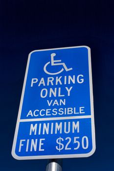 Handicapped parking sign with white lettering on blue backdrop.