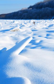 Winter landscape with frozen river against blue sky