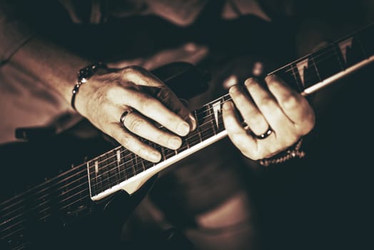 Rockman Playing Electric Guitar Closeup Photography. Hands on Guitar. Elegant Browny Color Grading.