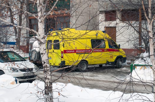 The yellow car of an emergency medical service costs at a house entrance. Tyumen, Russia
