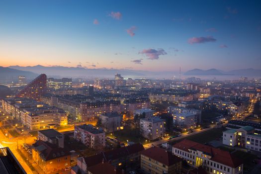 Cityscape of Slovenian capital Ljubljana at dusk. Alps mountains in background.