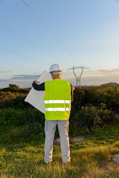 Electrical Engineer, Controls Power Line and wind turbines at sunset outdoors in the countryside