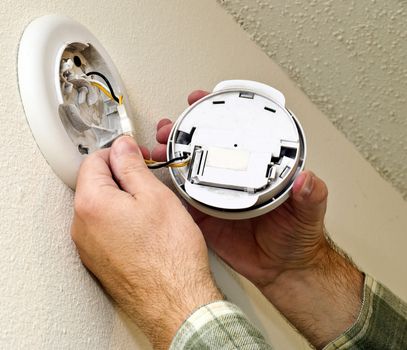 Close up hands installing smoke alarm in home.