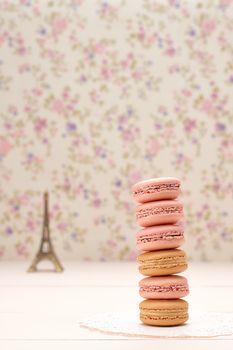 Macarons french dessert, stack. Eiffel Tower, souvenir from Paris, Fresh pastel dessert. Creative wedding set, vanilla wood, floral background. Romantic, still life. Retro vintage 