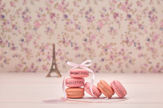 Macarons french dessert. Eiffel Tower, souvenir from Paris, Fresh pastel dessert, pink ribbon. Creative wedding set, vanilla wood, floral background. Romantic, still life. Retro vintage 