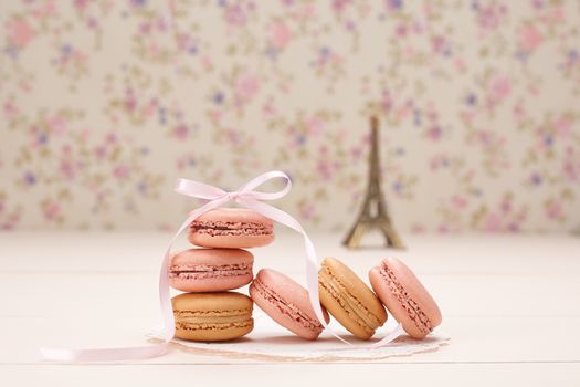 Macarons french dessert. Eiffel Tower, souvenir from Paris, Fresh pastel dessert, pink ribbon. Creative wedding set, vanilla wood, floral background. Romantic, still life. Retro vintage 