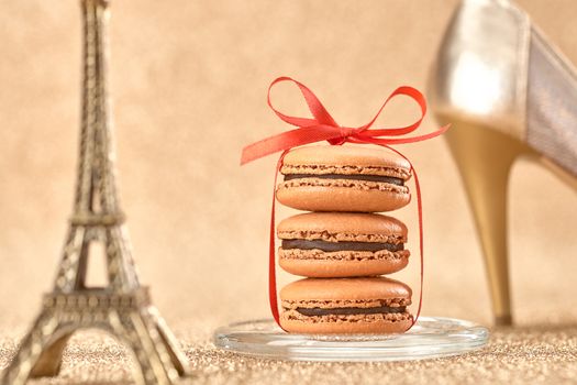 Macarons french dessert, Luxury shiny shoes high heels, Eiffel Tower, souvenir from Paris, red ribbon. Vintage retro romantic style. Unusual creative art greeting card, gold background, bokeh