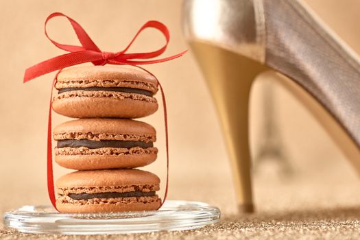 Macarons french dessert, Luxury shiny shoes high heels, Eiffel Tower, souvenir from Paris, red ribbon. Vintage retro romantic style. Unusual creative art greeting card, gold background, bokeh
