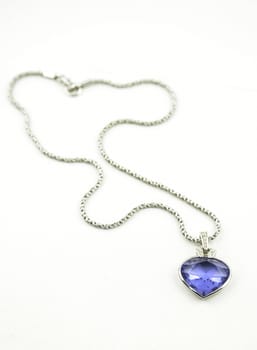 A beautiful pendant with a blue gemstone on the silver neckless isoalted on white studio background.