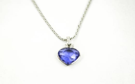 A beautiful pendant with a blue gemstone on the silver neckless isoalted on white studio background.