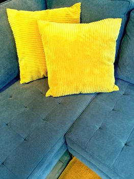 Blue sofa decorated with two bright yellow cushions.