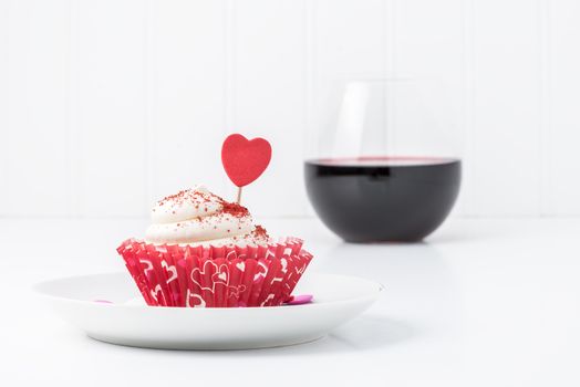 Red velvet cupcake served with a glass of red wine.
