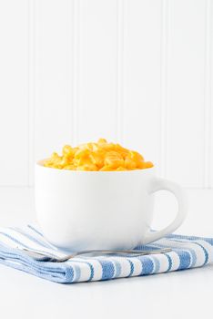 Mug filled with creamy cheddar macaroni and cheese.