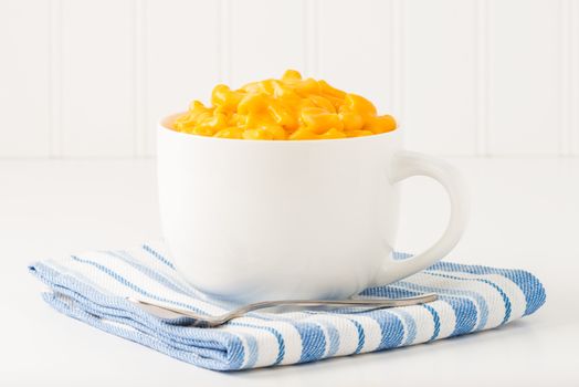 Mug filled with creamy macaroni and cheese.