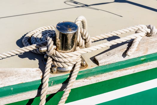 Fragmentary view details of knots and ropes on the yacht moored in the dock. 
Oarlock and rope on a sailboat.