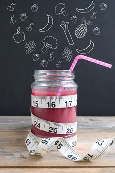 Healthy lifestyle fruits and vegetables sketched on a chalkboard appearing to fall into a smoothie jar with measuring tape