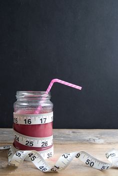 Berry smoothie with tape measure next to a chalkboard