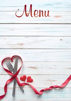 Heart shape silk red ribbon around a fork and knife on a menu background