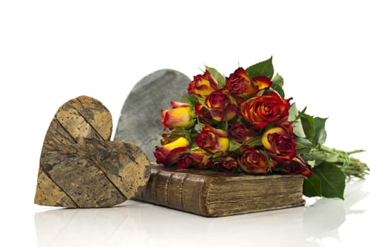 old book with red and yellow roses and wooden heart valentines card
