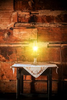 Burning Oil Lamp on the Aged Wooden Table in the Vintage Cabin Scenery.