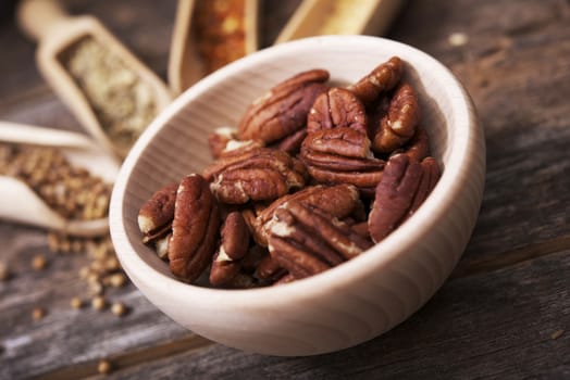 Pecans in the Small Wooden Bowl with Other Spices in the Background.