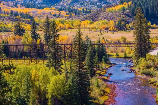 Colorado Fall Foliage. Yellow Aspen Trees, River and Old Railroad Tracks Bridge. Colorado, United States.