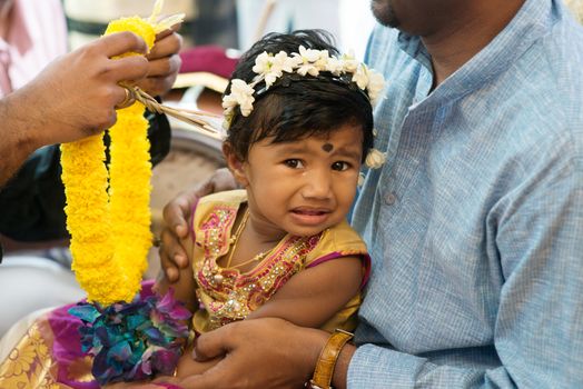 Baby girl received flower garland from priest. Traditional Indian Hindus ear piercing ceremony. India special rituals.