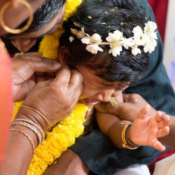 Baby girl crying during the karnavedha events. Traditional Indian Hindus ear piercing ceremony. India special rituals.