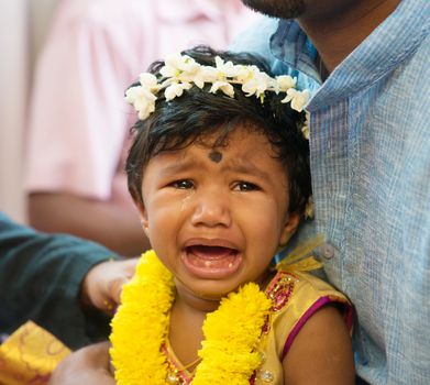 Baby girl crying after karna vedha events. Traditional Indian Hindus ear piercing ceremony. India special rituals.