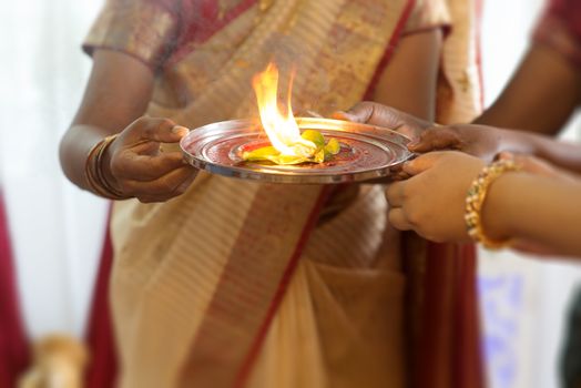 Traditional Indian woman performing special rituals at Hindu ear piercing ceremony for children.