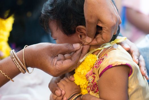 Baby girl crying in the karnavedha events. Traditional Indian Hindus ear piercing ceremony. India special rituals for children.