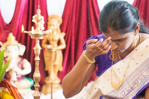 Hindu woman putting bindi or marking on her forehead during Indian traditional religious rituals, the tradition of Hinduism.