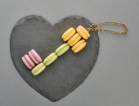 Still life, macarons sweet colorful, key shape, heart black placemat. French traditional delicious dessert with chain. Unusual creative romantic, gray background. Concept for love story.Valentines Day