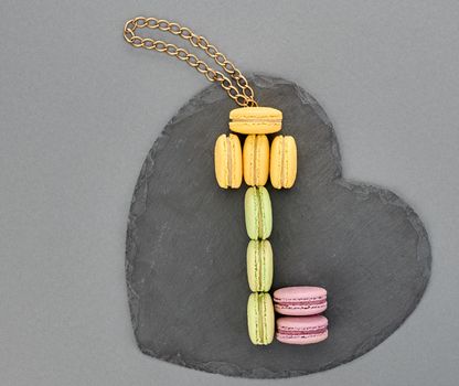 Still life, macarons sweet colorful, key shape, heart black placemat. French traditional delicious dessert with chain. Unusual creative romantic, gray background. Concept for love story.Valentines Day