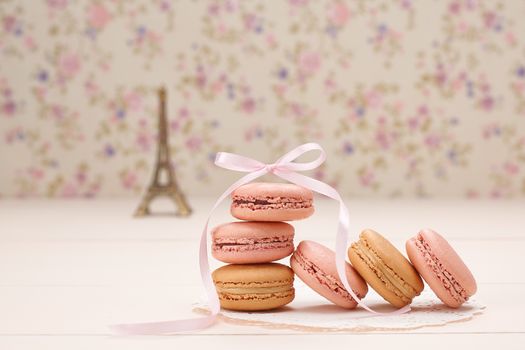 Macarons french dessert, still life. Eiffel Tower, souvenir from Paris, Fresh pastel dessert, pink ribbon. Creative wedding set, vanilla wood, floral background. Romantic, still life. Retro vintage 