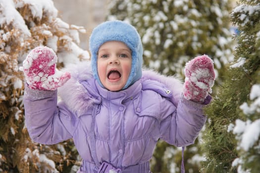 Five-year girl in a snowdrift snow against a snowy background Trees