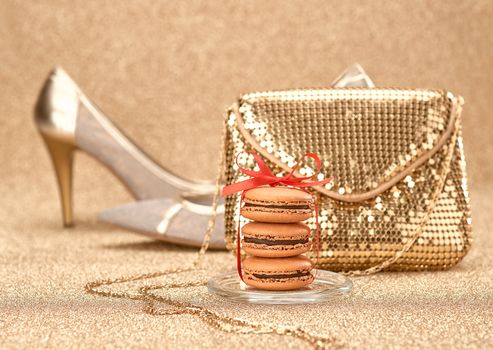 Macarons french dessert. Still life. Luxury shiny shoes high heels, glamor fashion handbag clutch, red ribbon. Vintage retro romantic. Unusual creative art greeting card, gold party background, bokeh