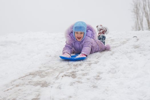 Five-year girl riding on a snowy icy hill